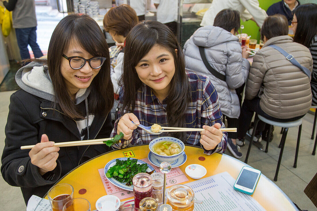Zwei junge Frauen genießen ihr Mittagessen im Mak's Noodle Restaurant, Central, Hong Kong Island, Hongkong, China