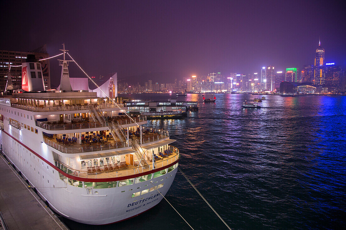 Cruise ship MS Deutschland, Reederei Peter Deilmann, at Ocean Terminal with skyline across Hong Kong Harbour at night, Tsim Sha Tsui, Kowloon, Hong Kong