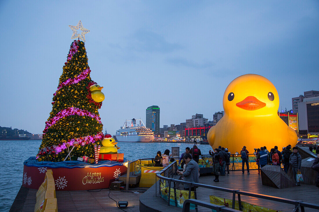 Christmas tree and giant rubber duck floating sculpture, designed by Dutch artist Florentijn Hofman, in harbor at dusk, Keelung, Northern Taiwan, Taiwan
