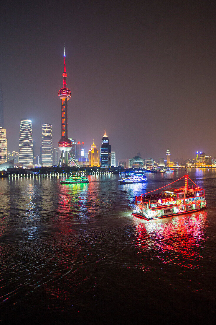 Sightseeing boats on the Huangpu River with Oriental Pearl Tower and Pudong skyline at night, Shanghai, China