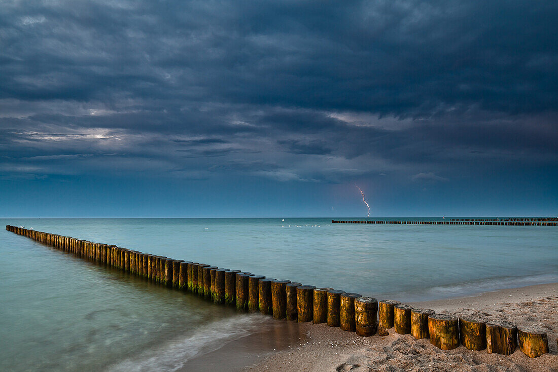 Buhnen am Strand im Abendlicht, Gewitter mit Blitz im Hintergrund, Zingst, Darß, Ostsee, Mecklenburg-Vorpommern, Deutschland