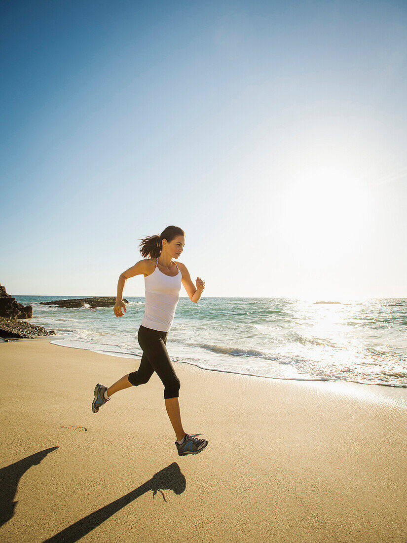Gemischtrassige Frau läuft am Strand, Laguna Beach, Kalifornien, USA
