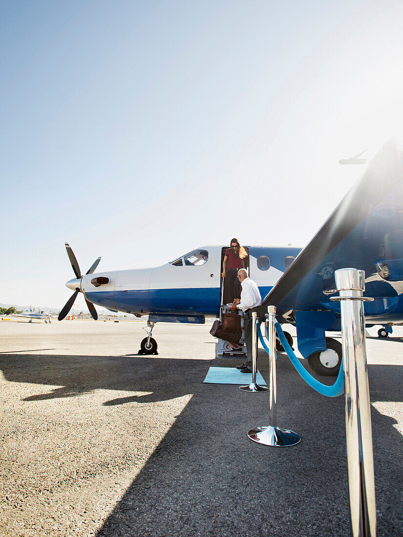 Business people disembarking airplane on runway, Burbank, California, USA