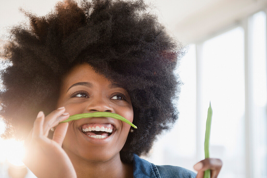 Mixed race woman playing with green beans, Jersey City, New Jersey, USA