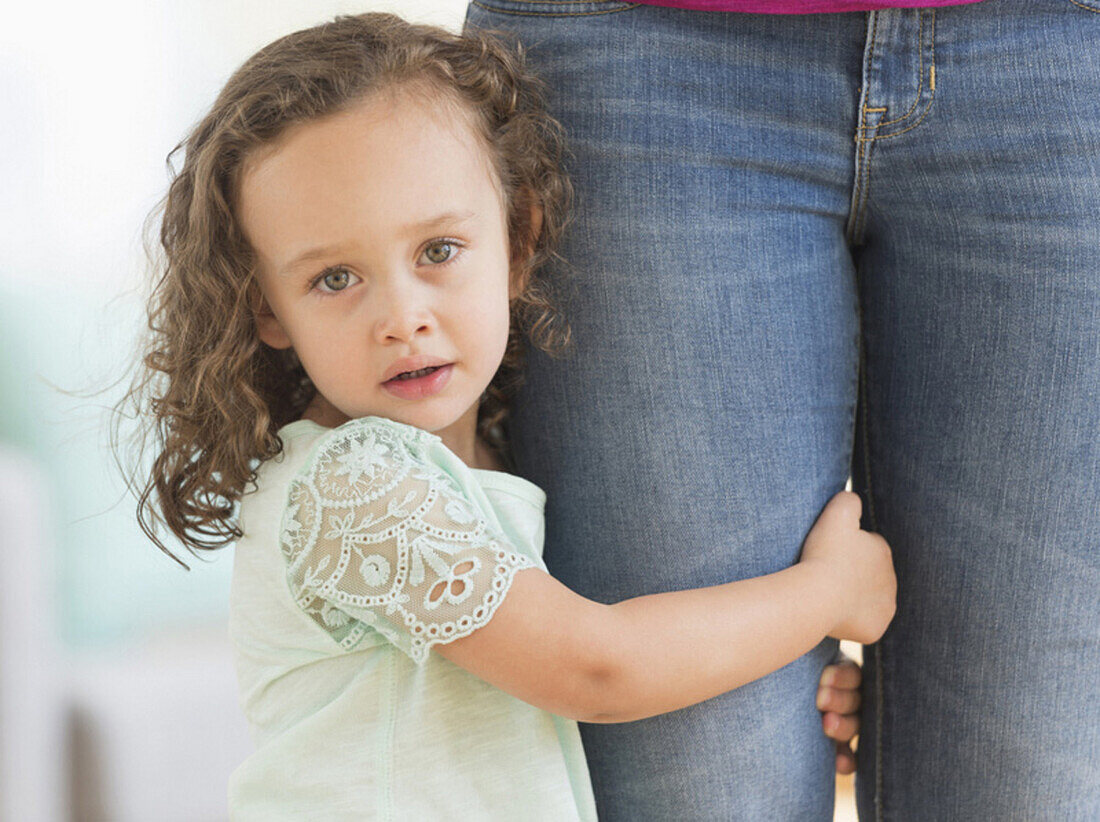 Mixed race girl clinging to mother's leg, Jersey City, NJ, USA