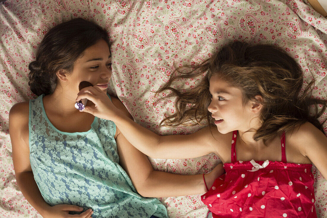 Mixed race sisters relaxing on bed, Norfolk, Virginia, USA