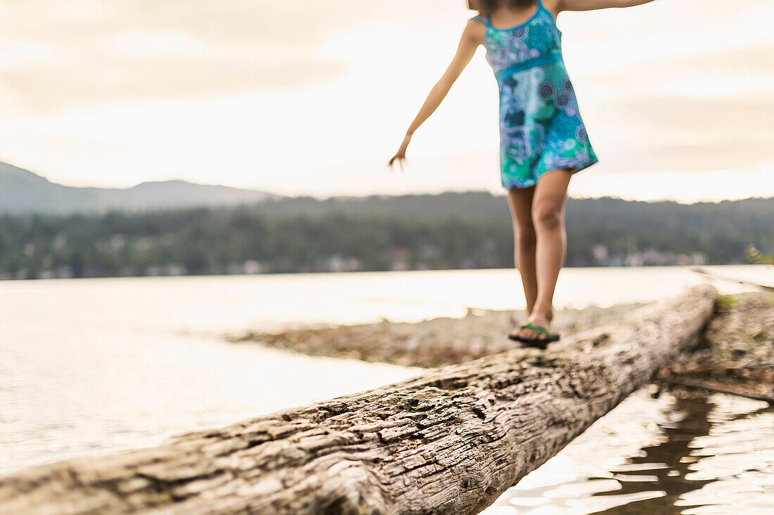 Mixed race girl walking on log, Bellingham, Washington, USA