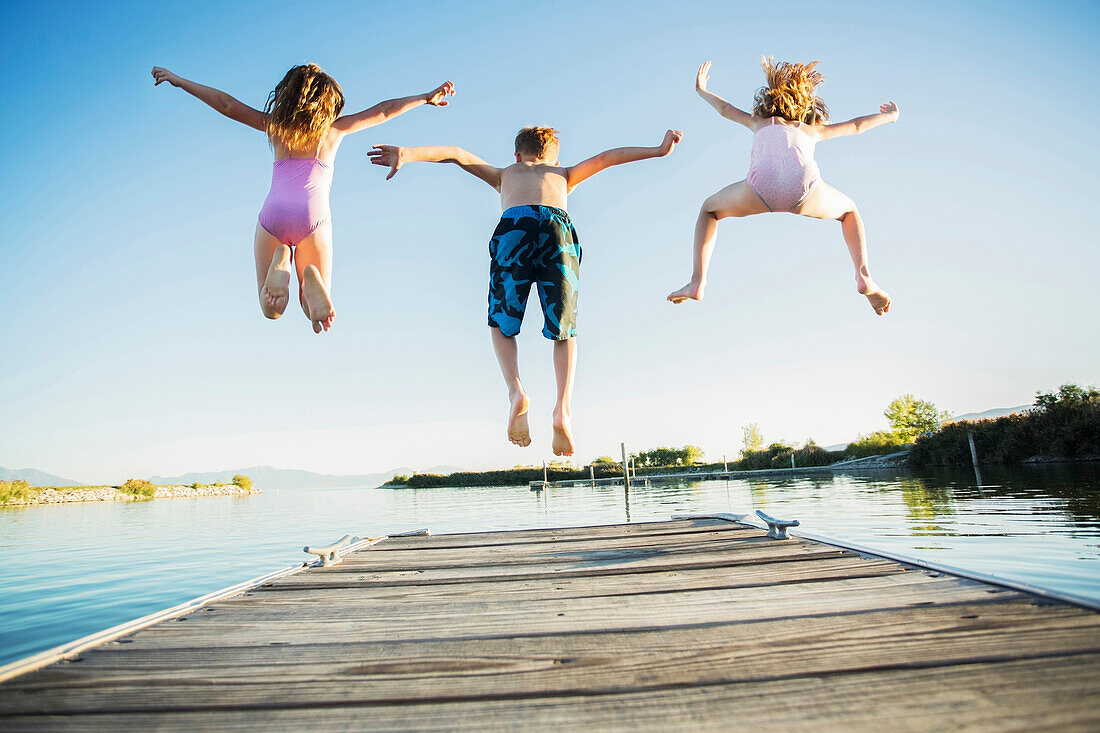 Caucasian children jumping off dock into lake, American Fork, Utah, USA