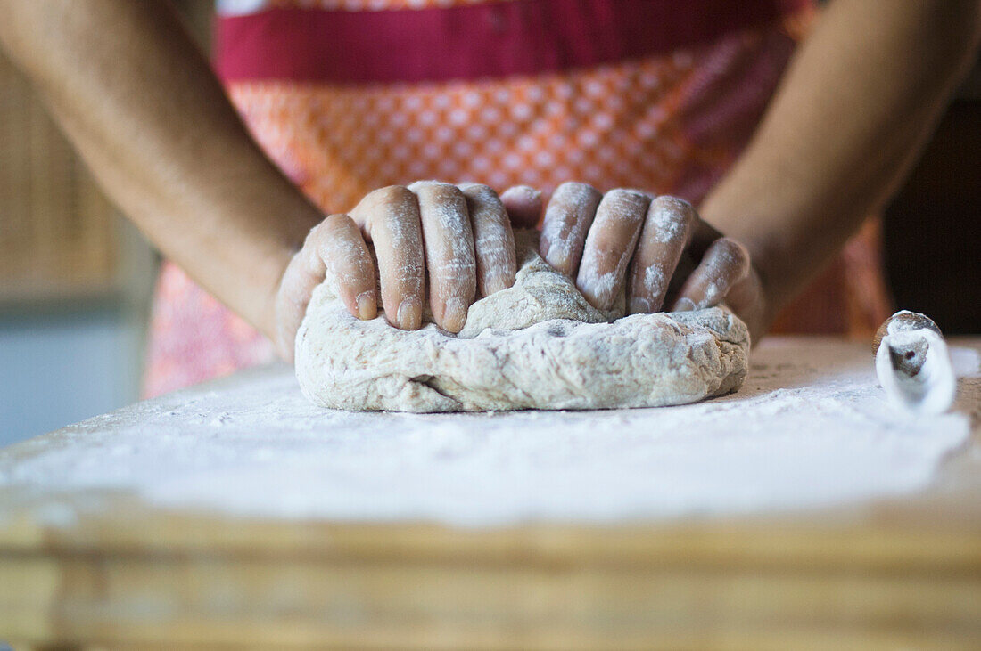 Mixed race woman kneading dough in kitchen, Austin, TX, USA