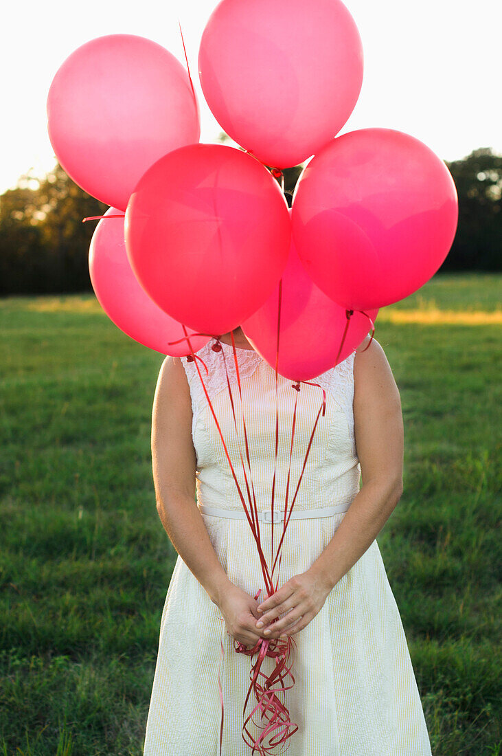 Mixed race woman with pink balloons in park, Austin, TX, USA