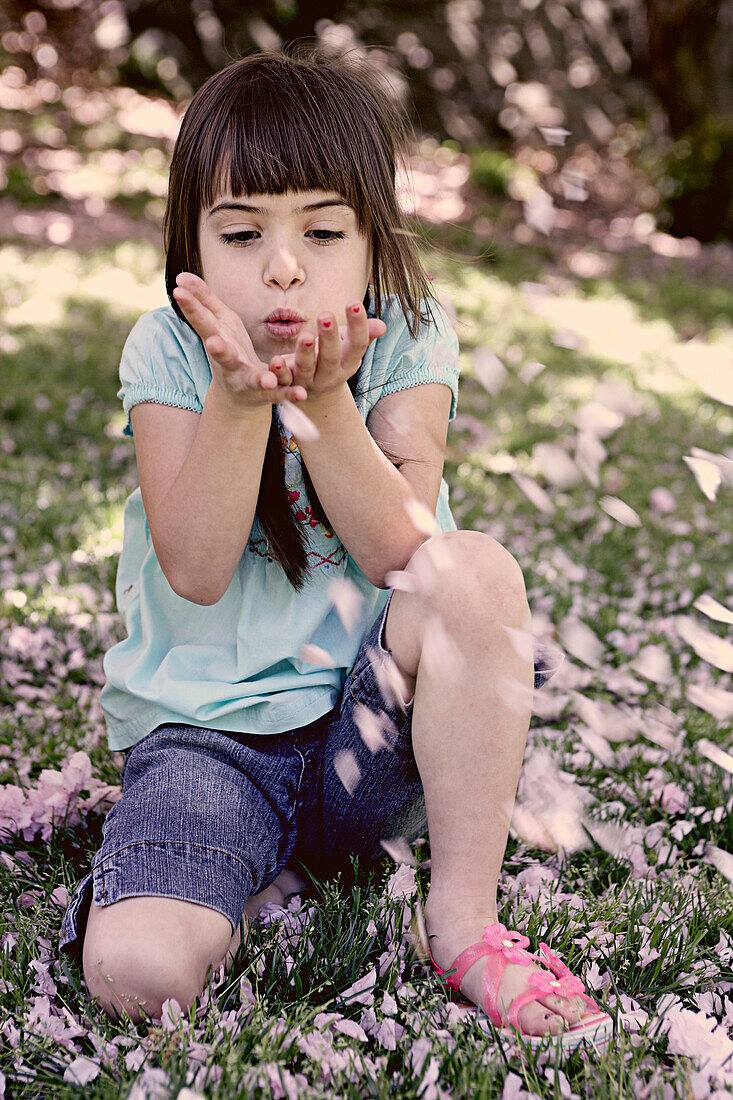 Mixed race girl playing with flowers in park, New York, New York, USA