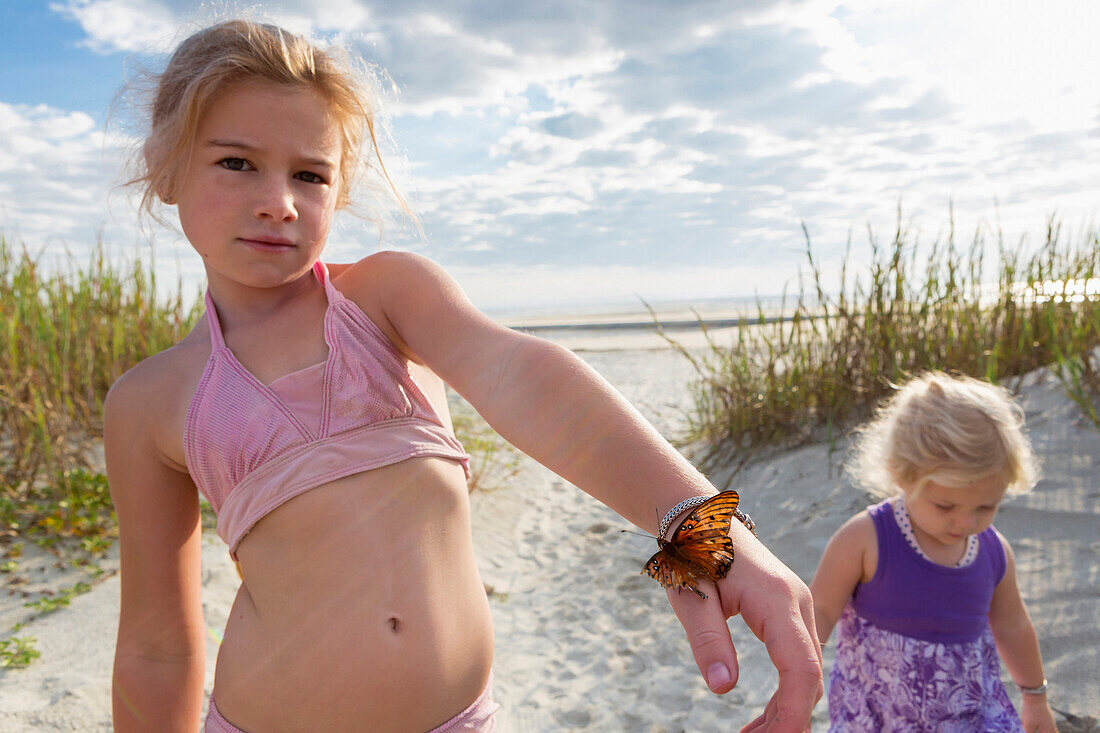 Caucasian girl holding butterfly on beach, Brunswick, Georgia, United States