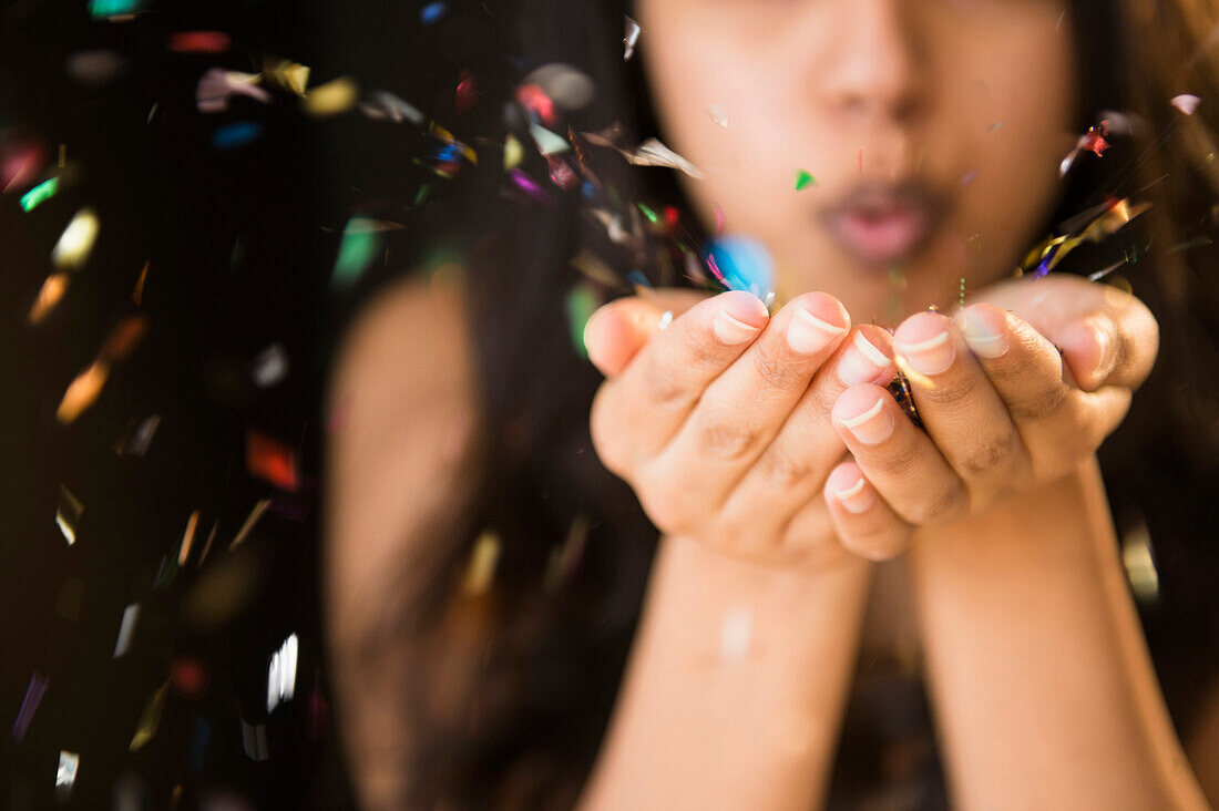 Close up of Asian woman blowing confetti from hands, Jersey City, New Jersey, USA