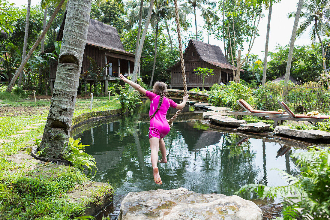 Caucasian girl swinging on rope in garden, Ubud, Bali, Indonesia, Ubud, Bali, Indonesia