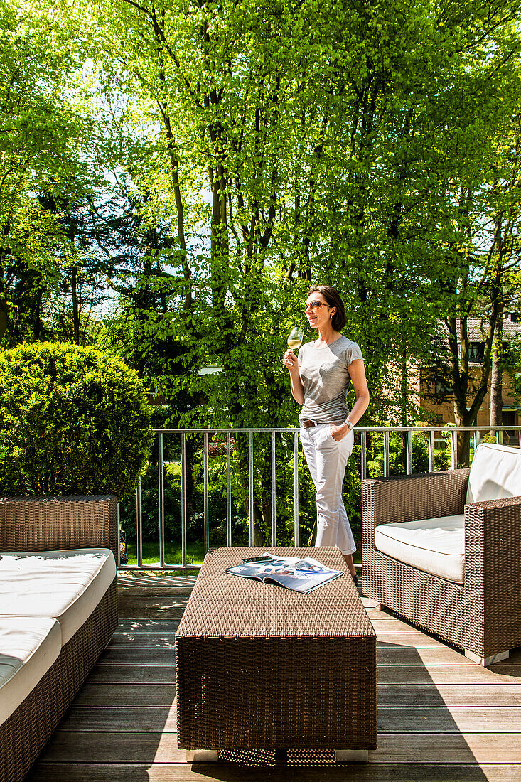 Woman with a glass of wine standing on the balcony, Hamburg, Germany