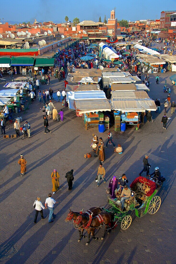 Restaurants, terraces, Kharbouch mosque and minaret, and tourists, Jemaa-el-Fna square, Marrakech, Morroco, North Africa.