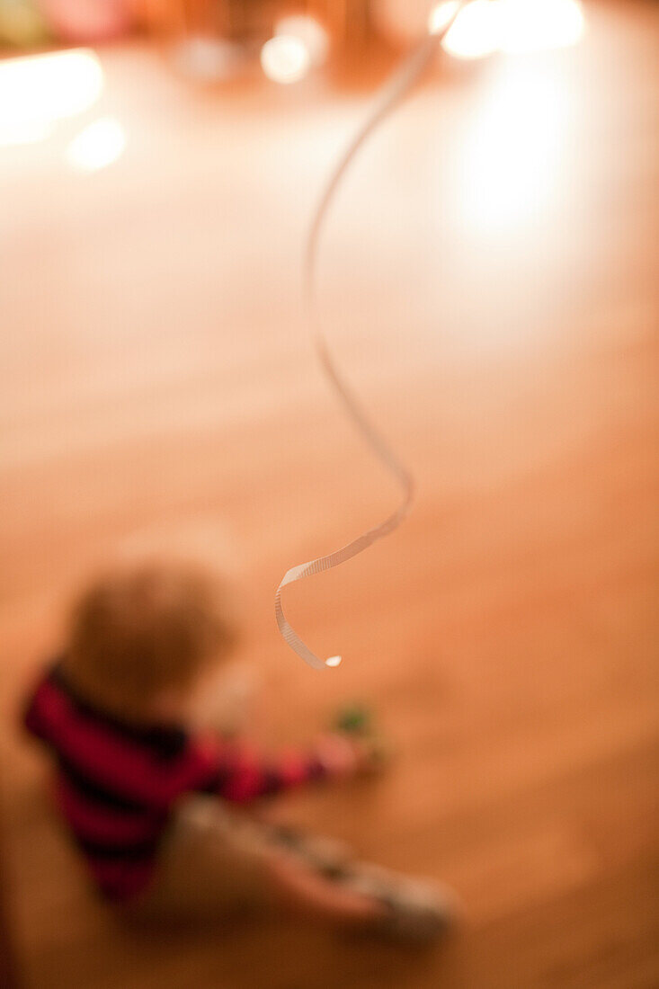 Young boy sitting on floor with balloon ribbon