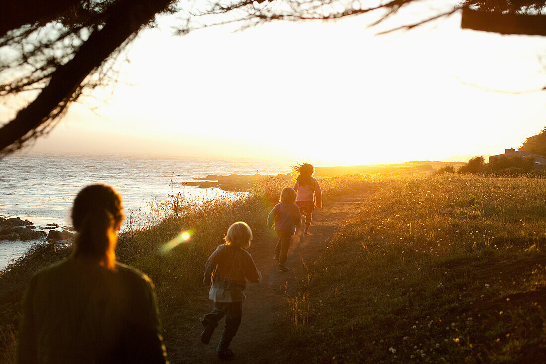 Family walking by coast at sunset