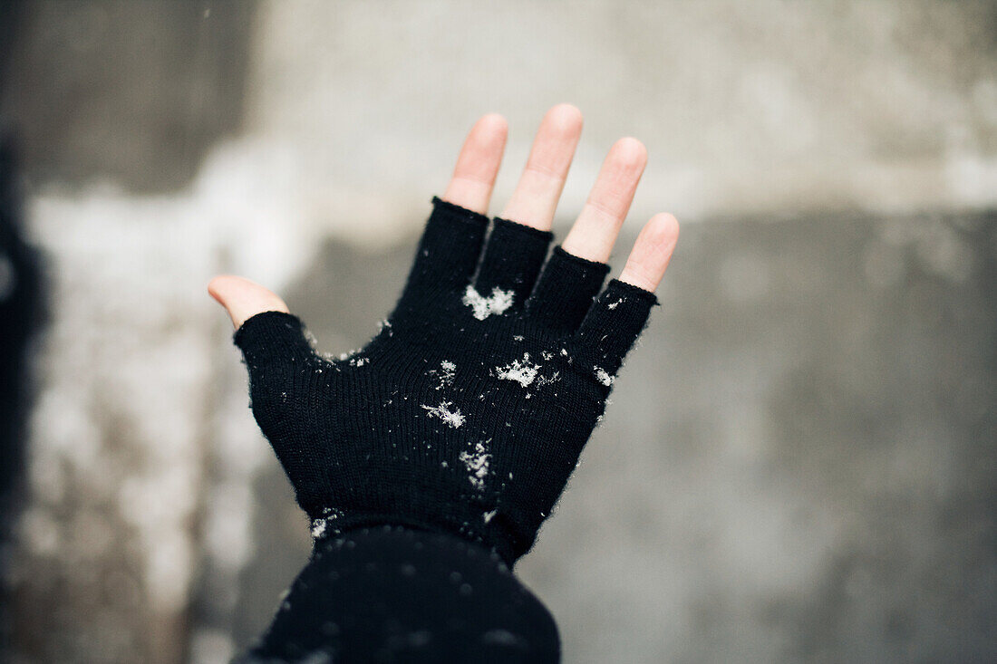 Person wearing fingerless glove in the snow
