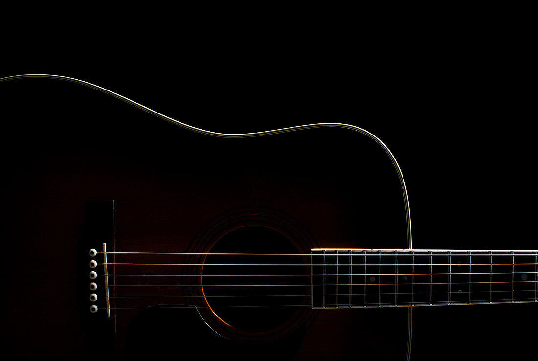 Acoustic guitar against black background