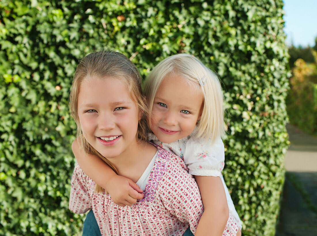 Girl carried by sister on back, smiling, portrait