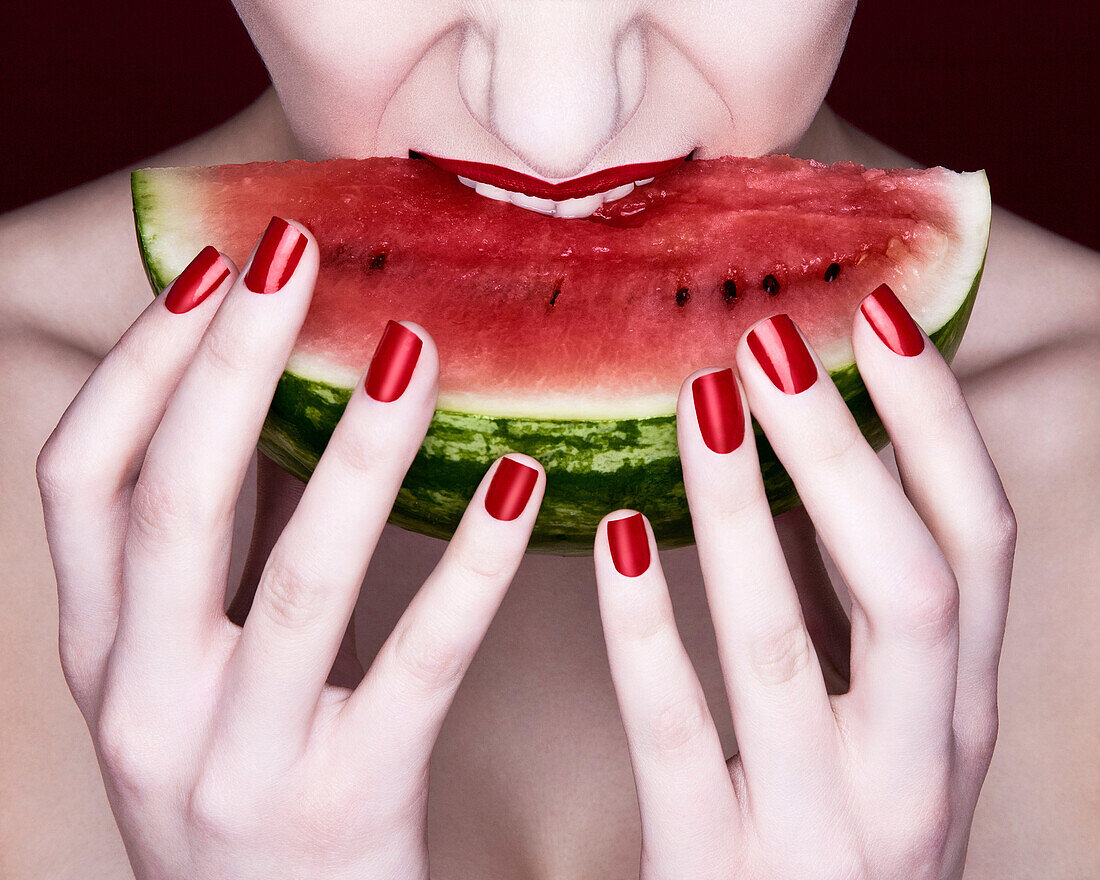 Frau beißt in Scheibe Wassermelone