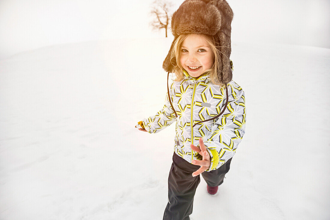 Girl wearing furry hat walking in snow