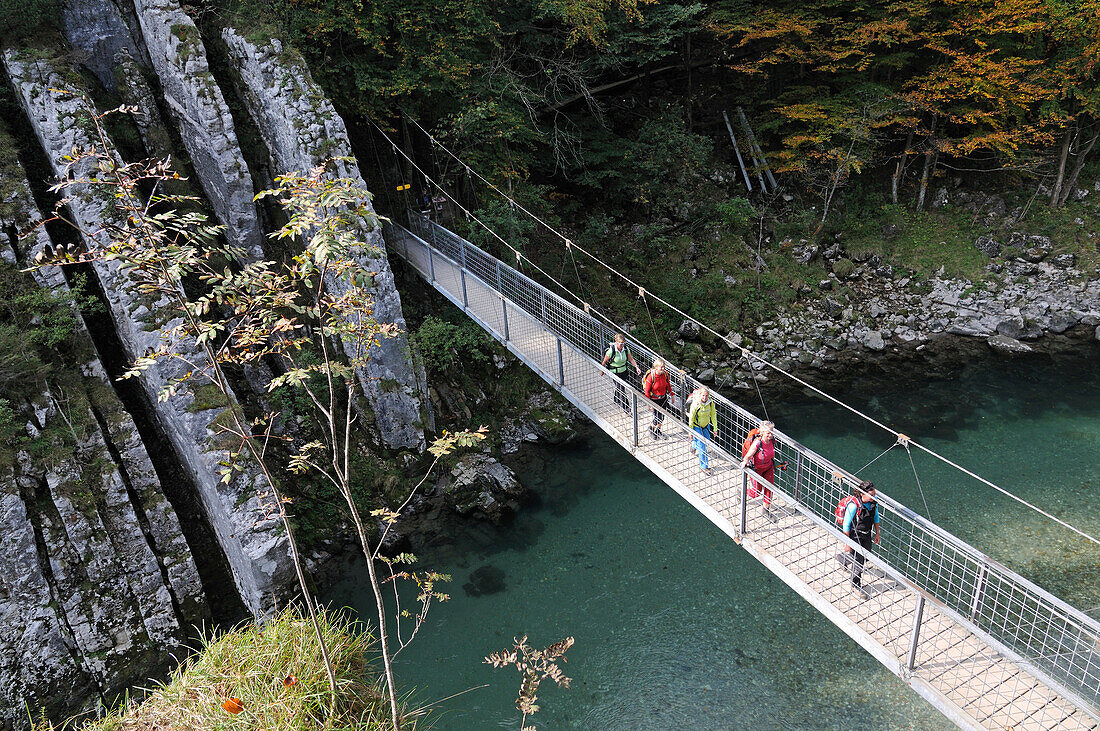 Female hikers passing a suspension bridge crossing Ache river at Klobenstein, Tyrol, Austria