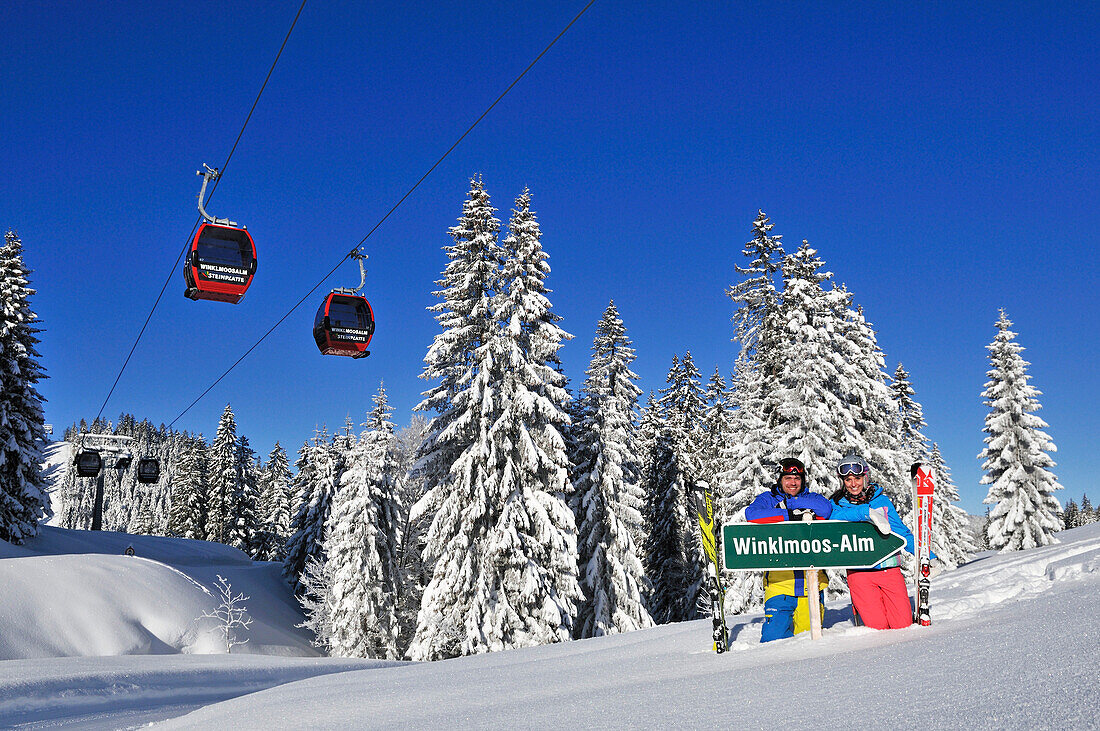 Skifahrer posieren an einem Schild, Skigebiet Winklmoosalm, Reit im Winkl, Chiemgau, Bayern, Deutschland