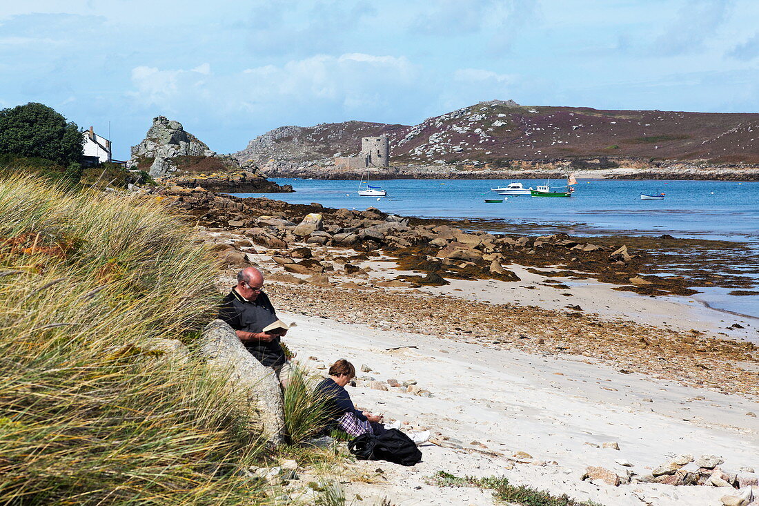 Couple reading on the beach, Anneka's Quay, Bryher, Isles of Scilly, Cornwall, England, Great Britain