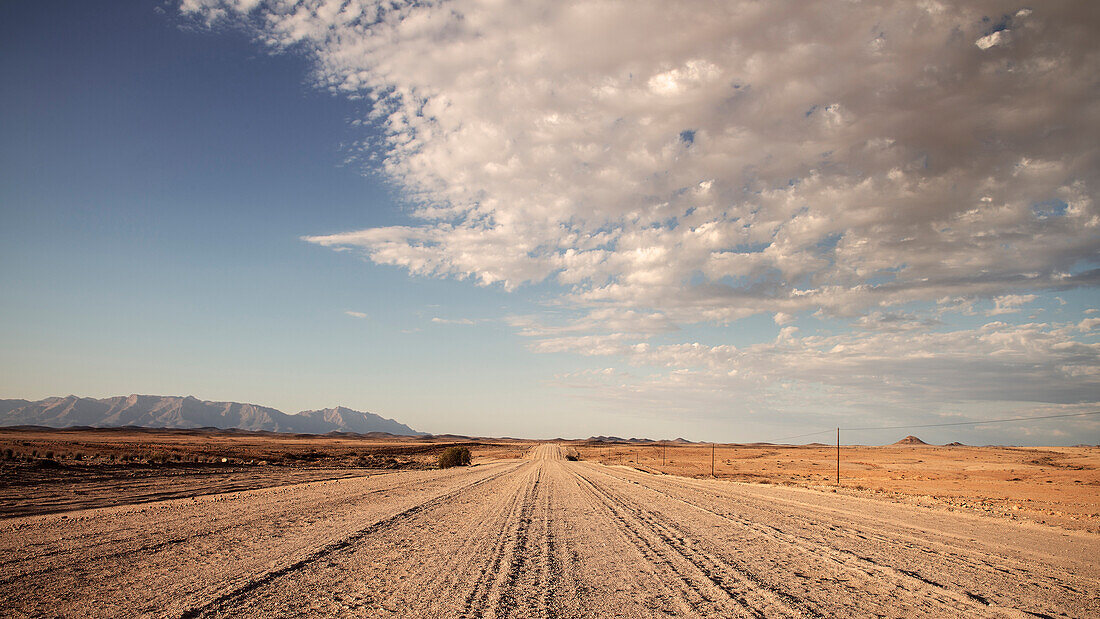 Seemingly endless sandy road towards Brandberg Mountain Range, Namibia, Africa