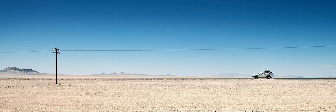 4x4 vehicle in the desert and electricity pylon close to Luderitz, Namibia, Africa