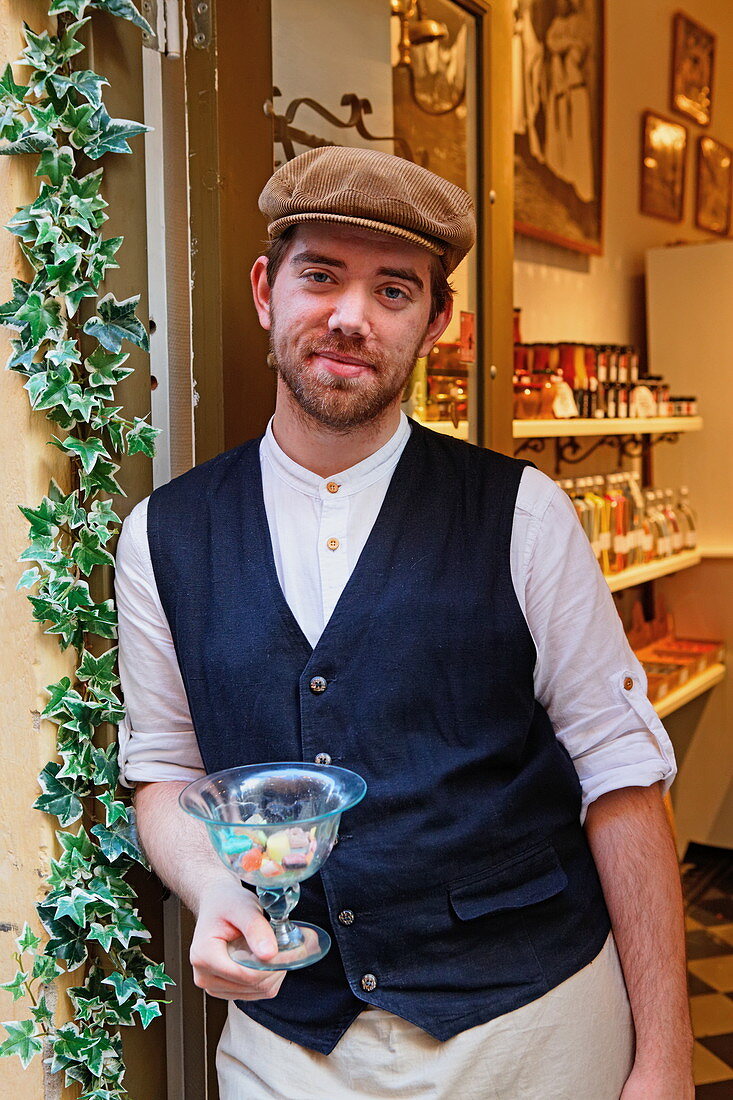 Sales man offering sweets at his shop, Gamla Stan, Stockholm, Sweden