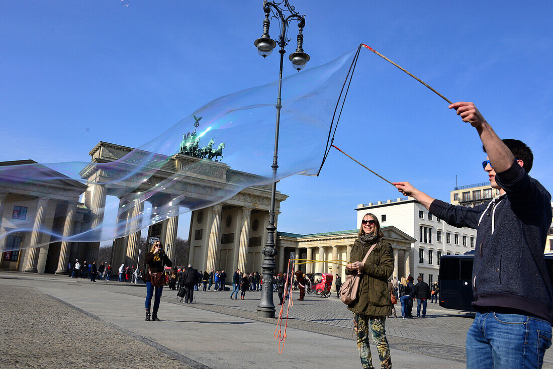 Man making bubbles, Pariser place with Brandenburg gate, Berlin, Germany