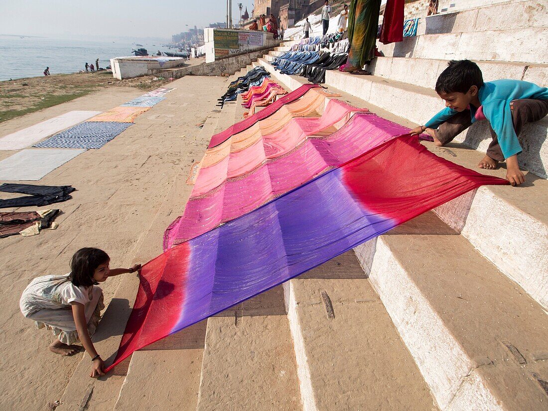 Children helping each other in drying clothes at Varanasi, Uttar Pradesh, India.