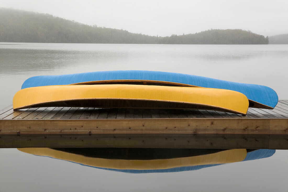 Blue And Yellow Canoes On Cottage Dock On A Misty Morning, Algonquin Park, Ontario