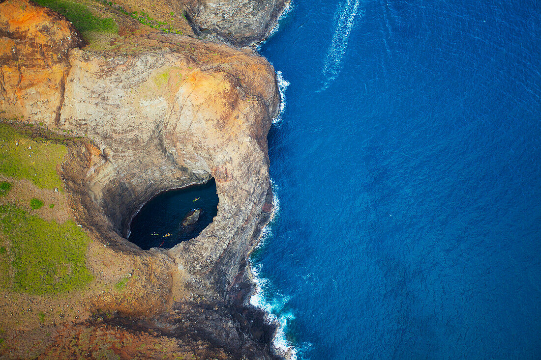 'Aerial view of the rugged coastline and tide pool in a hole along an hawaiian island; Hawaii, United States of America'