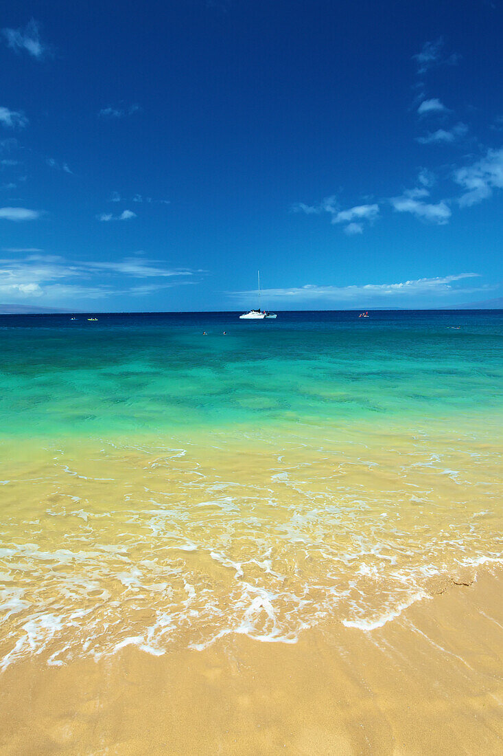 'A boat mooring in the water in the distance as viewed from the beach on the coast of an hawaiian island; Hawaii, United States of America'