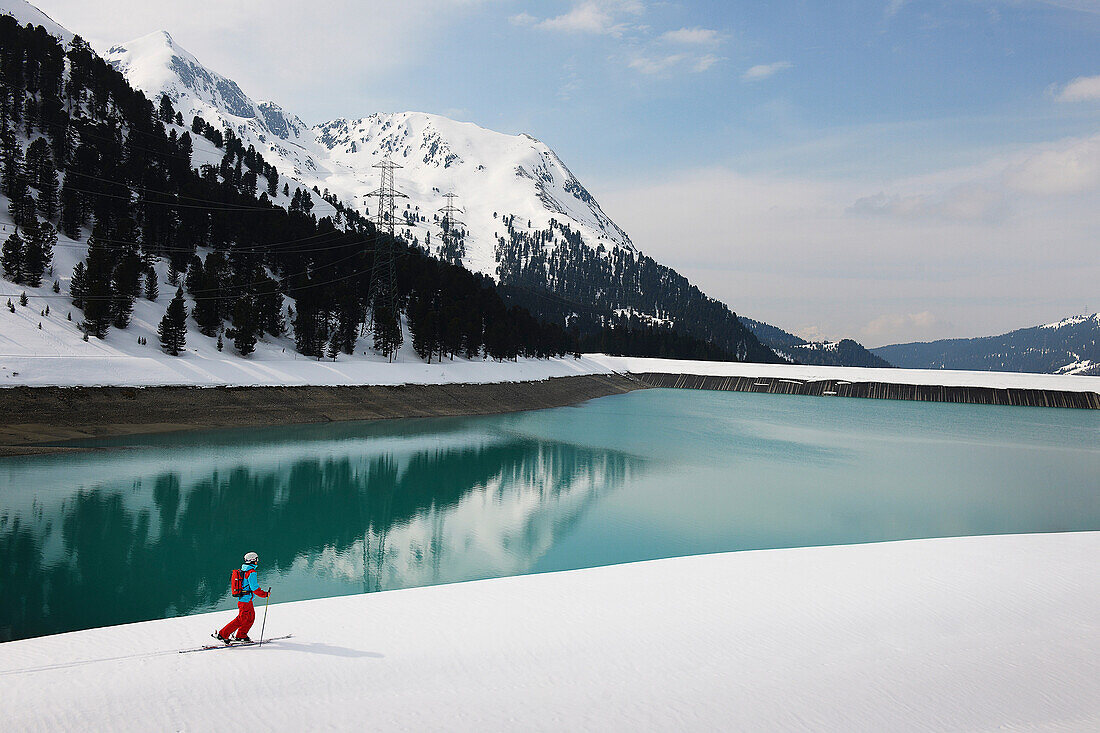 Solitary skier by lake and mountain, Kuhtai, Austria