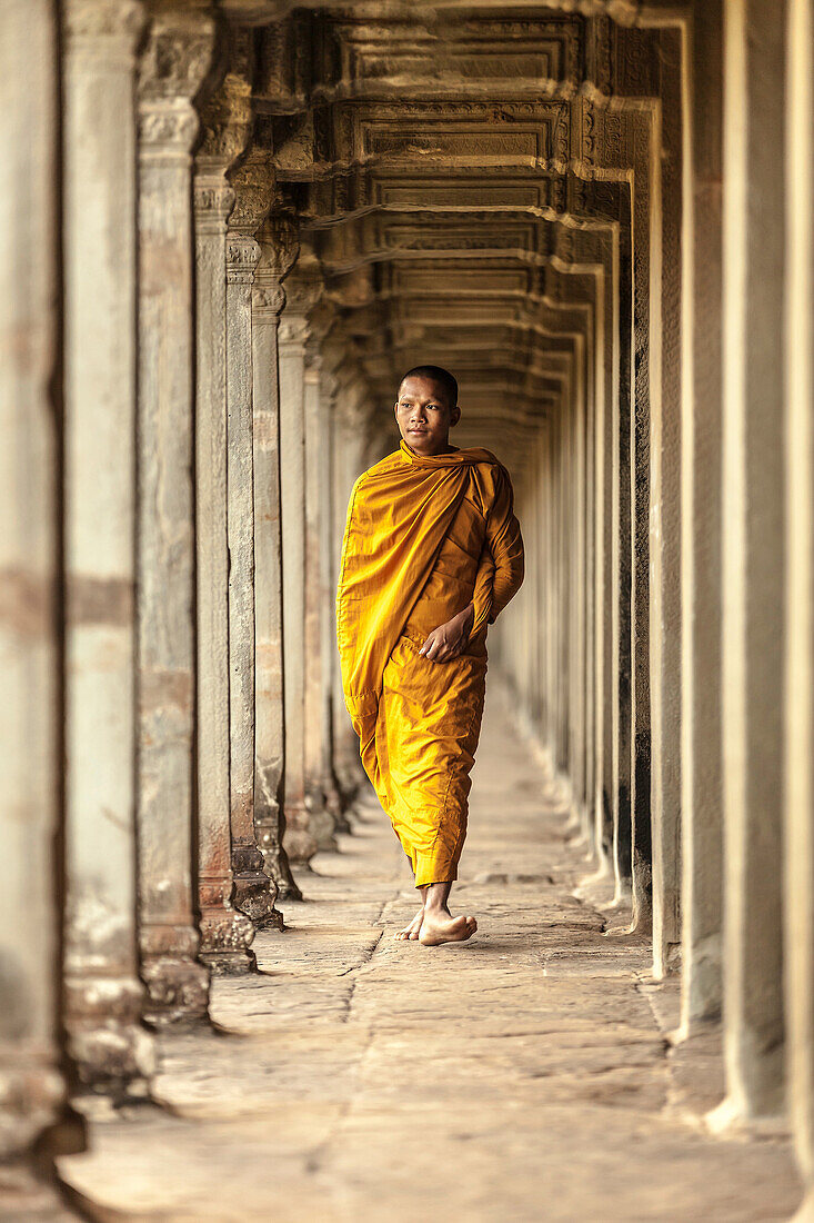Young Buddhist monk walking through temple, Angkor Wat, Siem Reap, Cambodia