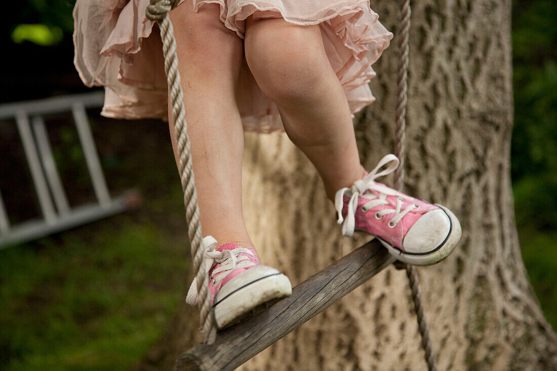 Cropped shot of girl's legs, climbing rope ladder