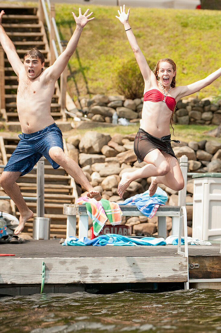 Young couple jumping into lake