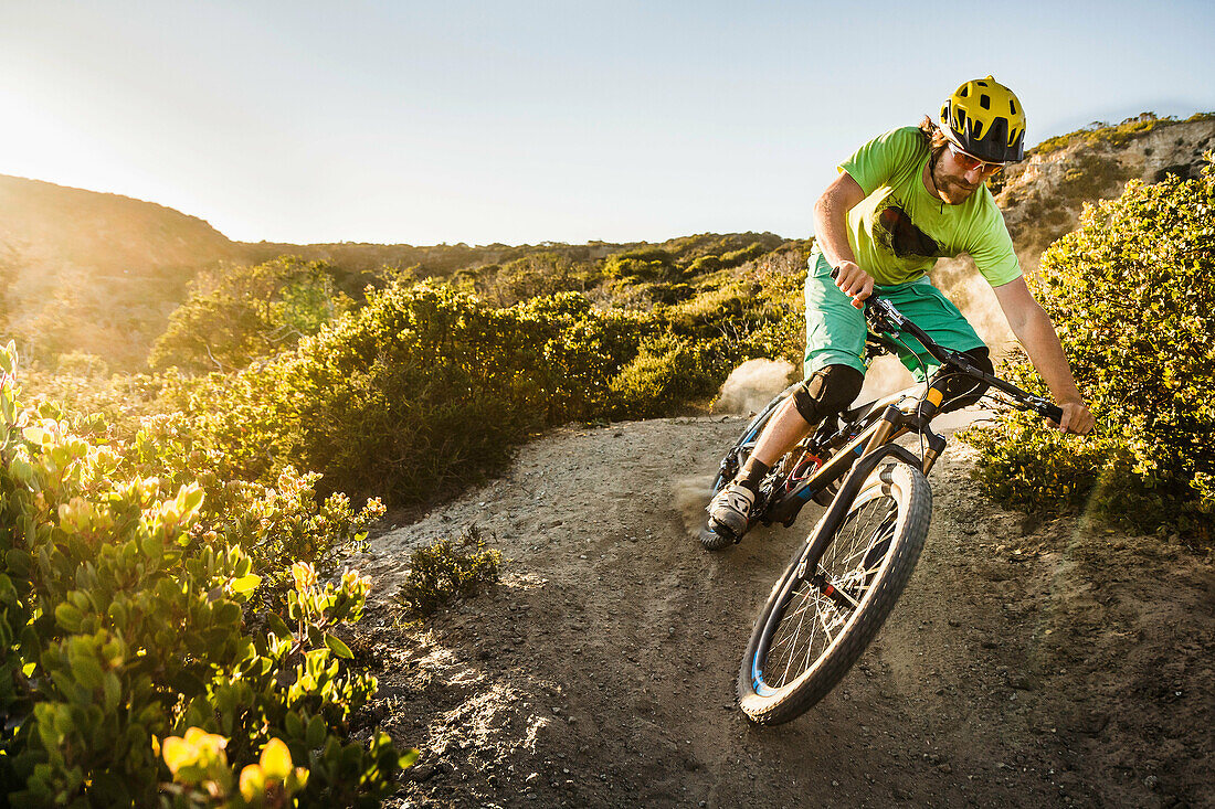 Young man mountain biking on dirt track, Monterey, California, USA