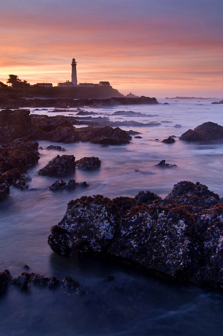 Clouds at surnise over waves and coastal rocks at low tide at Pigeon Point Lighthouse, San Mateo County coast, California.