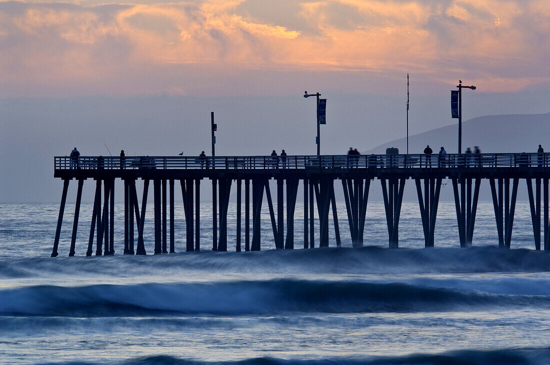 Sunset light over the pier and ocean waves at Pismo Beach, San Luis Obispo County coast, California.