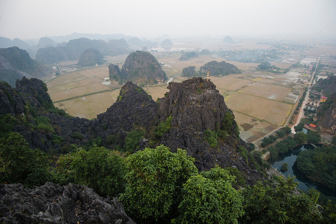 View from the top of a mountain over Tam Coc area at sunset with carsic formations in the background, Ninh Binh, Vietnam
