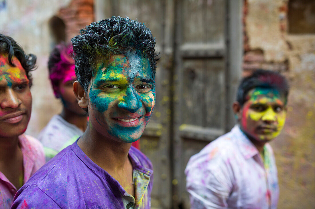 Guys with color painted faces having fun in the streets during Holi festival, Mathura, India