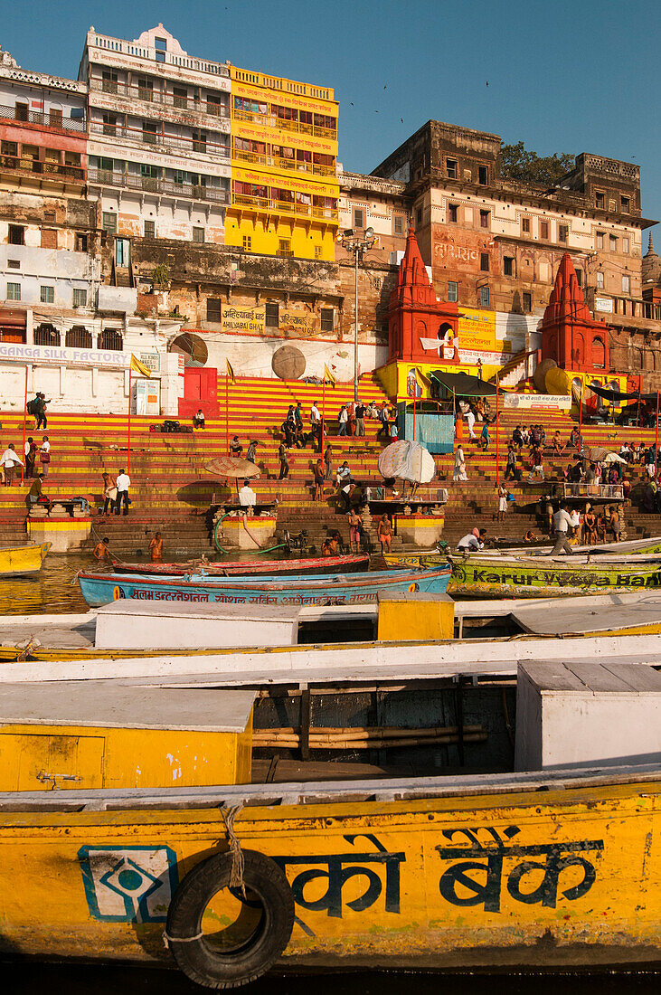 Colorful boats, stairs and buildings of Varanasi seen from the Ganges river in the early morning light, Varanasi, India