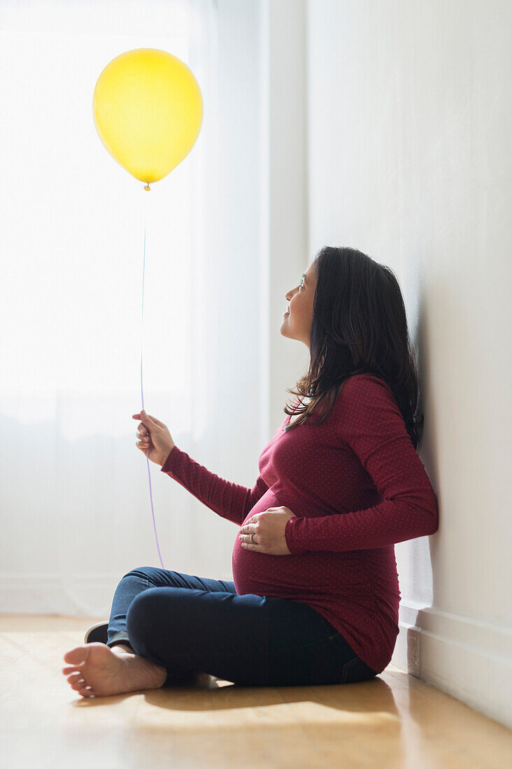 Pregnant Hispanic woman holding balloon, Jersey City, NJ, USA