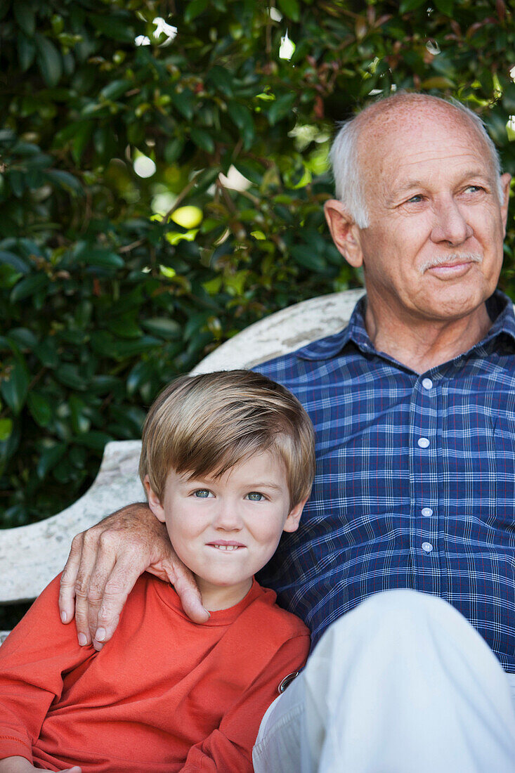 Caucasian boy sitting with grandfather on bench, Cape Town, Western Cape, South Africa